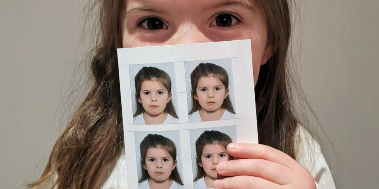 Une fillette tient dans sa main ses photos d'identité réalisées chez Clergeon Photo.