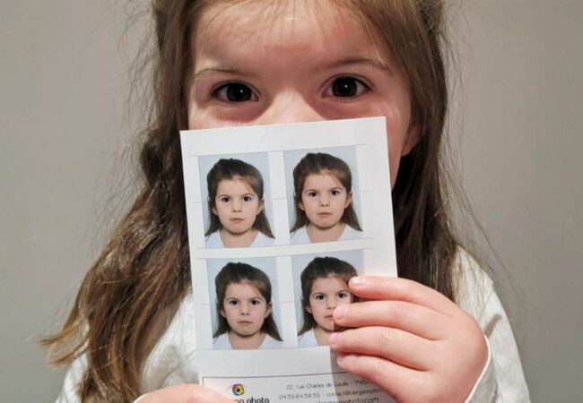 Une fillette tient dans sa main ses photos d'identité réalisées chez Clergeon Photo.