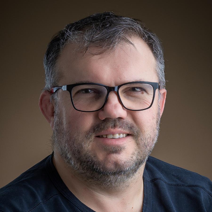 Portrait d’un homme salarié chez Clergeon Photo Portrait d'un homme avec des lunettes noires, une courte barbe et souriant.